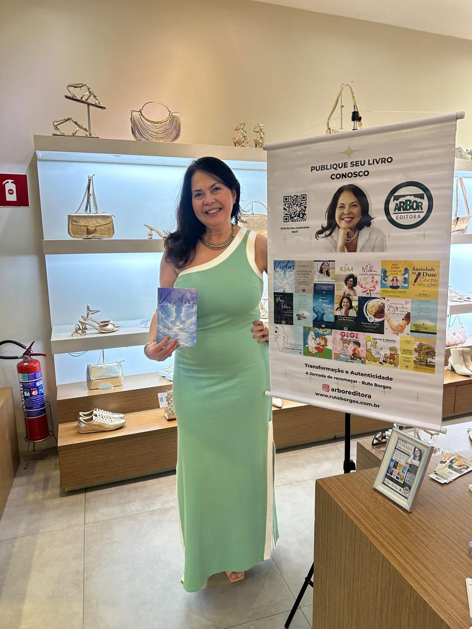Rute Borges em evento de lançamento, segurando um de seus livros